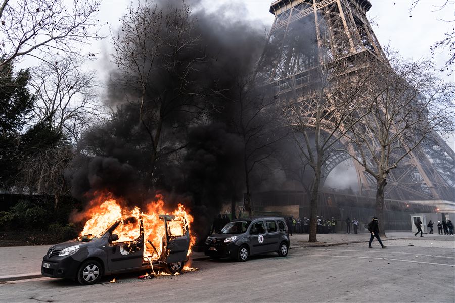 Voiture en feu près de la tour Eiffel lors d'une manifestation