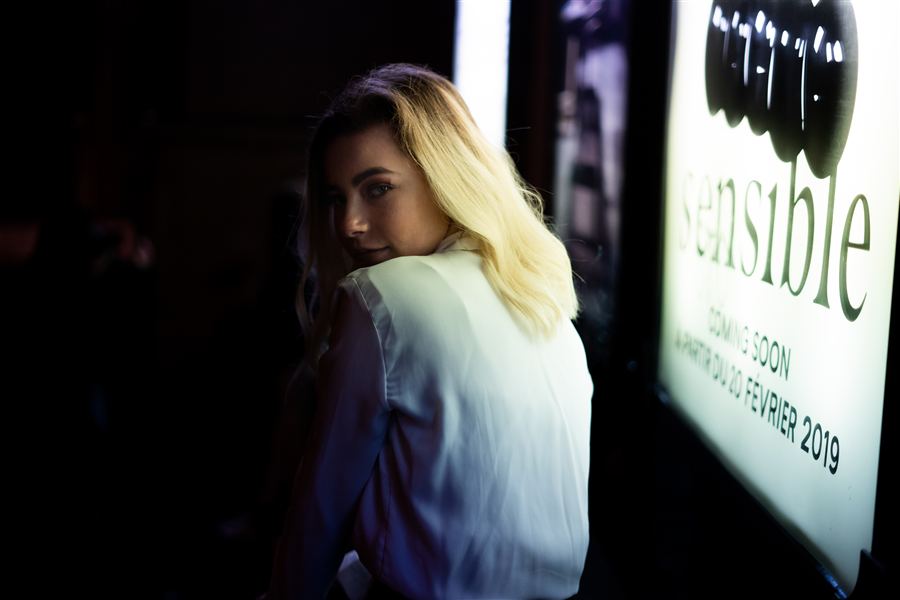 Portrait nocturne d'une femme près d'une enseigne lumineuse